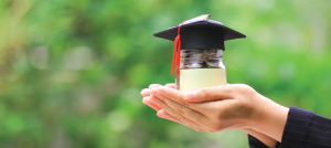 Manos con un vaso que contiene moneas.