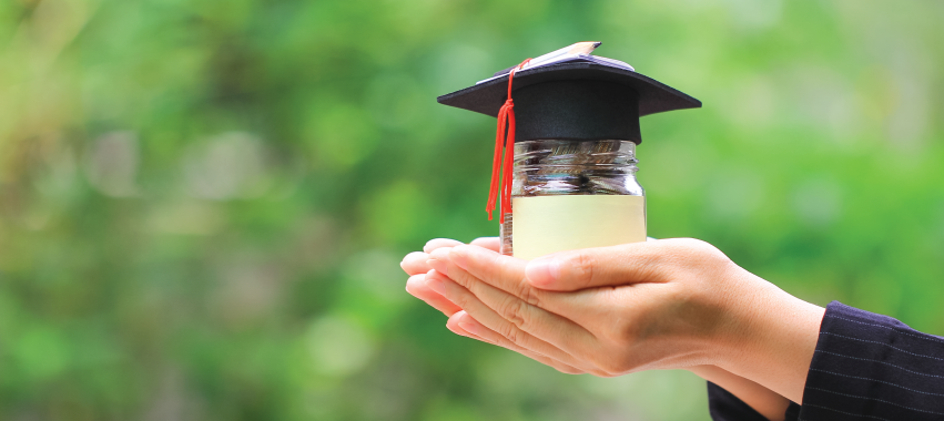 Manos con un vaso que contiene moneas.