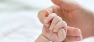 Persona sosteniendo mano de bebe