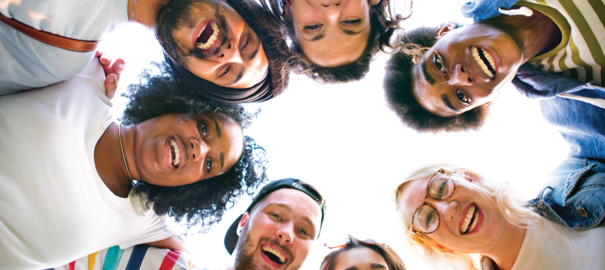 Grupo multiétnico de personas formando un círculo y sonriendo.