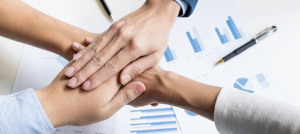 Manos unidas. En el fondo, hojas impresas con estadísticas