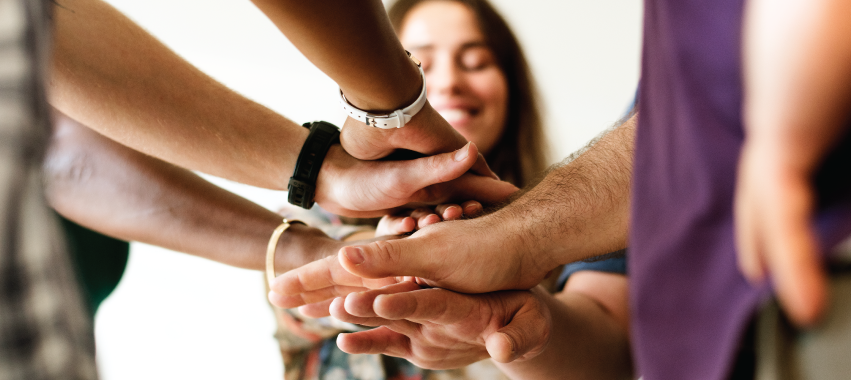 Manos unidas. En el fondo, una mujer sonriendo.