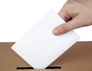 Mano ingresando un voto en una urna.