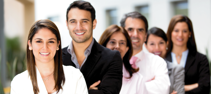 Seis personas, de porte administrativo, uno detrás del otro sonríen a la cámara.