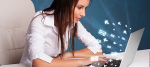 Mujer observa en un computador portátil cómo íconos de cartas y flechas salen de la pantalla.