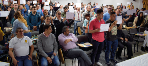 Grupo de personas, de pie, sostienen certificados en sus manos.