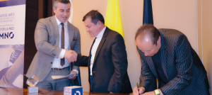 Monseñor Jorge Alberto Ossa saluda de mano a un hombre mientras el padre Diego Rendón firma un documento.