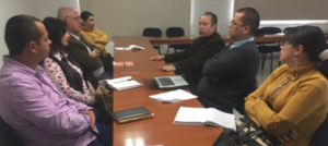 Siete personas sentadas en torno a una mesa de madera.