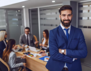 Hombre soriente frente a una cámara en medio de una sala de juntas.