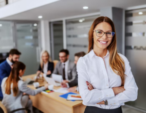Mujer soriente frente a una cámara en medio de una sala de juntas.