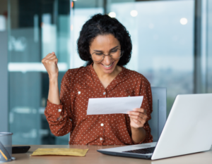 Mujer con expresión de felicidad al leer en una hoja de papel.