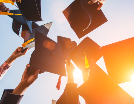 Manos sosteniendo virretes en una ceremonia de graduación
