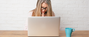 Mujer orando en frente de un computador portátil.