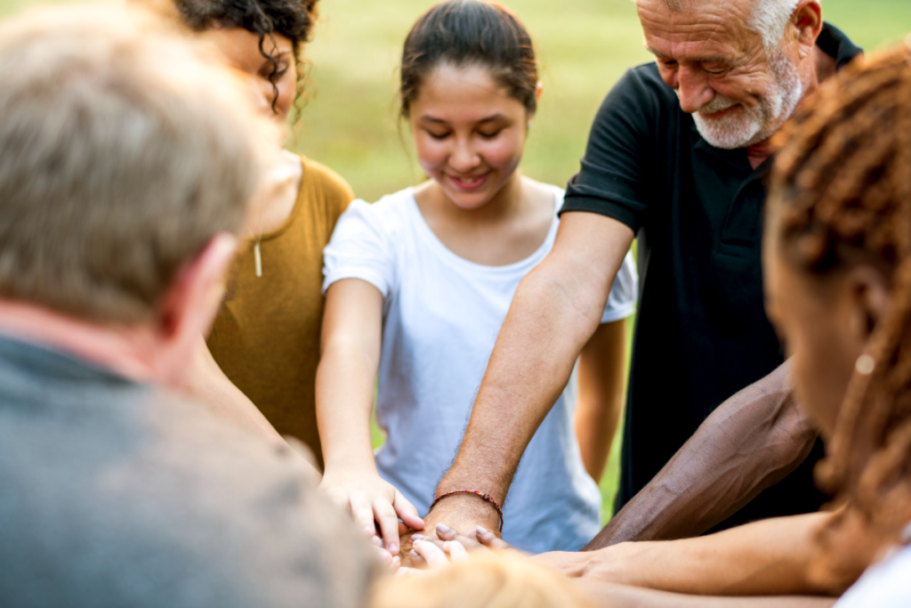 Grupo de personas se dan la mano en señal de unidad y cooperación.