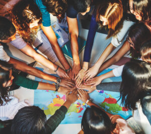 Personas juntando las manos, debajo un mapa mundial